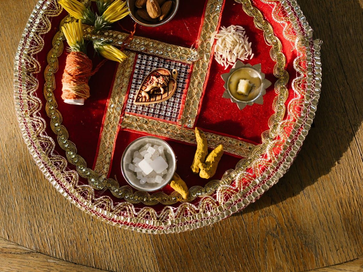 A decorated puja thali with rice, sugar, turmeric and a lamp